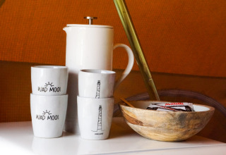 Tazze, caffettiera e ciotola in legno con snack sul tavolo nel teepee Bell Escape Family a Little Canvas Escape.