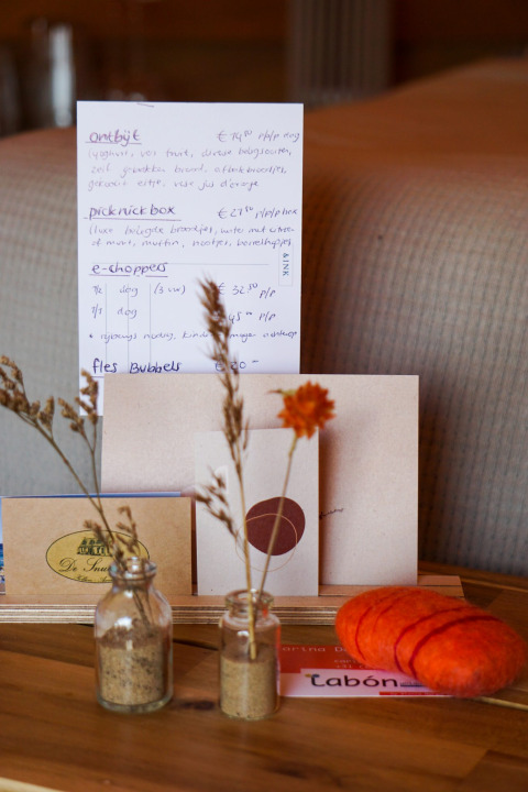 Teepee tent interior with menu card, dried flowers in jars, and decor at Little Canvas Escape, Netherlands.