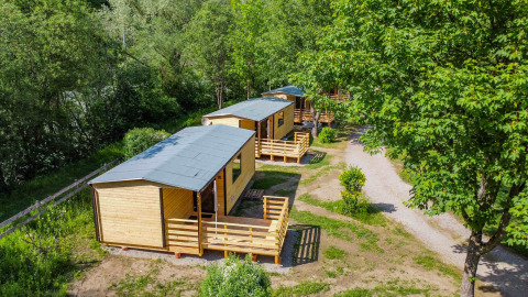 Luftaufnahme von Holzhütten im Grünen im Drau Camping Sachsenburg, Kärnten, Österreich.