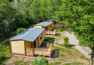 Vue aérienne de cabanes en bois entourées de verdure au Drau Camping Sachsenburg, Carinthie, Autriche.