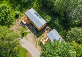 Aerial view of two cozy cabins at Drau Camping Sachsenburg holiday park, nestled among lush greenery.