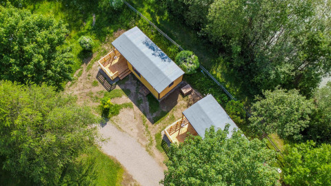 Luchtfoto van twee gezellige chalets op Drau Camping Sachsenburg, omringd door groen in Karinthië.