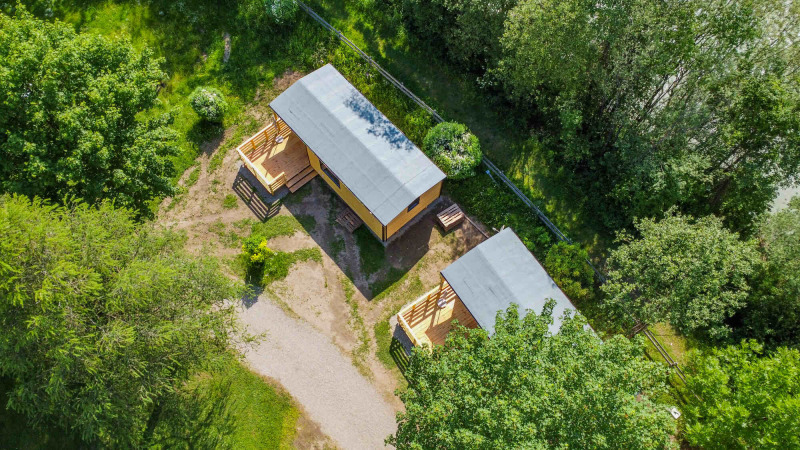 Vue aérienne de deux chalets au Drau Camping Sachsenburg, entourés de verdure luxuriante en Autriche.