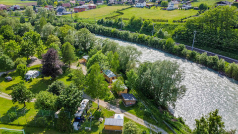 Vista aérea del parque vacacional Drau Camping Sachsenburg en Carintia, Austria, con río y caravanas.