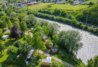 Vista aerea di Drau Camping Sachsenburg, villaggio turistico in Carinzia, Austria, con fiume e case mobili.