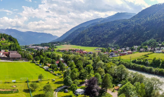 Vue panoramique du Drau Camping Sachsenburg avec rivière, champs et montagnes en Carinthie, Autriche.