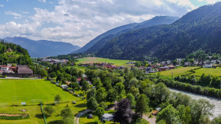 Vista panorámica de Drau Camping Sachsenburg con río, campos y montañas en Carintia, Austria.