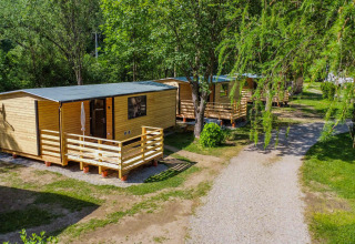 Holzhütten und viel Grün im Drau Camping Sachsenburg, Ferienpark in Kärnten, Österreich, naturnah gelegen.