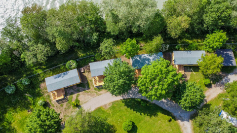 Aerial view of Drau Camping Sachsenburg holiday park in Carinthia, Austria showing cabins and lush greenery.