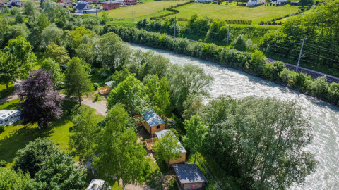 Vista aérea del parque vacacional Drau Camping Sachsenburg junto al río en Carintia, Austria, rodeado de naturaleza.