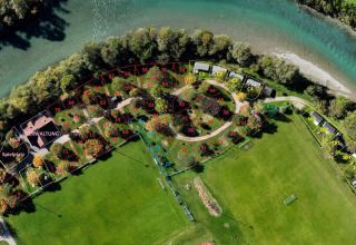 Luchtfoto van Drau Camping Sachsenburg in Karinthië, Oostenrijk, met genummerde kampeerplaatsen en rivier.