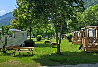 Vakantiepark Drau Camping Sachsenburg in Karinthië, Oostenrijk, met stacaravans, picknicktafels en bomen.