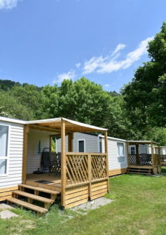 Casas móviles en Drau Camping Sachsenburg, Carintia, Austria, rodeadas de árboles y naturaleza tranquila.