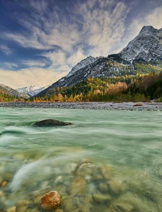 Impresionante paisaje de río y montaña en los alrededores de Kramsach, Tirol, Austria, bajo un cielo dramático.