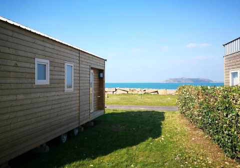 Casas móviles en Camping Seasonova Les 7 Iles en Bretaña, Francia, con vistas al mar y una isla al fondo.