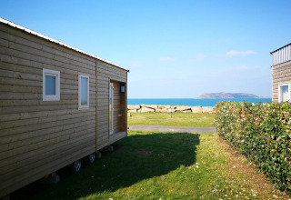 Mobilhytter ved Camping Seasonova Les 7 Iles i Bretagne, Frankrig, med udsigt over havet og en ø i baggrunden.