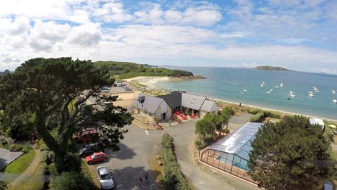 Camping Seasonova Les 7 Iles en Bretaña, Francia, con playa, mar, piscina y barcos en el horizonte.