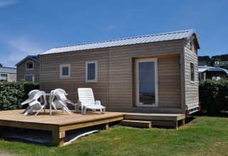 Piccola casetta in legno con terrazza e sdraio al Camping Seasonova Les 7 Iles in Bretagna, Francia.