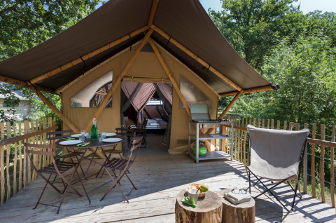 Safari tent Canadian Tent at Village Huttopia Lagoa de Óbidos, Portugal, with deck, dining set and forest view.