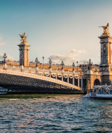 Vista impresionante del puente Pont Alexandre III en París, con esculturas doradas y luz cálida del atardecer.