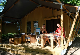 Two people sit at a table outside a large tent at Camping Seasonova L'Etang des Bois in France.