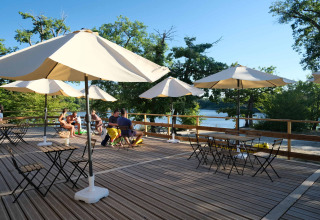 Udendørs terrasse med parasoller, borde og stole ved Camping Seasonova L'Etang des Bois i Centre-Val de Loire.