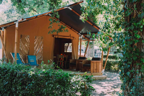 Cozy safari tent lodge at Camping Seasonova L'Etang des Bois in Centre-Val de Loire, France, surrounded by greenery.