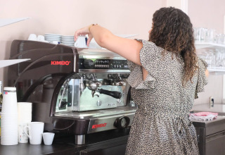 Donna che prepara il caffè con una macchina per espresso al Camping Seasonova L'Etang des Bois, Centre-Val de Loire, Francia.