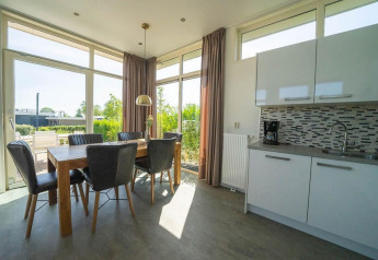 Zona pranzo e cucina con grandi finestre nella lodge Pavilion a EuroParcs Veluwemeer nei Paesi Bassi.