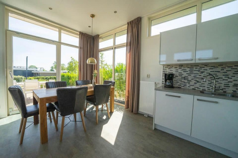 Zona de comedor y cocina con ventanas grandes en la cabaña Pavilion en EuroParcs Veluwemeer, Países Bajos.