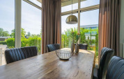 Lichte eetruimte in de Pavilion lodge bij EuroParcs Veluwemeer, Nederland, met grote ramen en zicht op tuin.