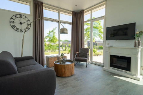 Moderne woonkamer in de Pavilion lodge bij EuroParcs Veluwemeer, Nederland, met grote ramen en open haard.