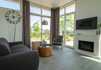 Stijlvolle woonkamer in Pavilion lodge bij EuroParcs Veluwemeer, Nederland, met haard en grote ramen.