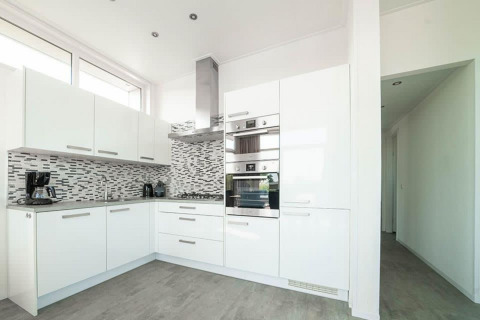 Cocina blanca moderna en el Pavilion de EuroParcs Veluwemeer, Países Bajos, con salpicadero de azulejos.