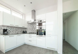 Cocina blanca moderna en el Pavilion de EuroParcs Veluwemeer, Países Bajos, con salpicadero de azulejos.