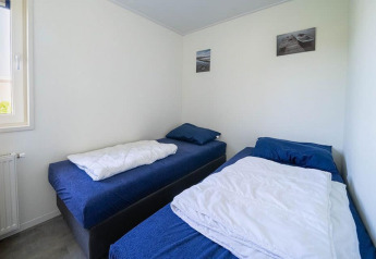 Tweepersoonskamer met blauwe lakens en witte muren in Pavilion bij EuroParcs Veluwemeer in Nederland.