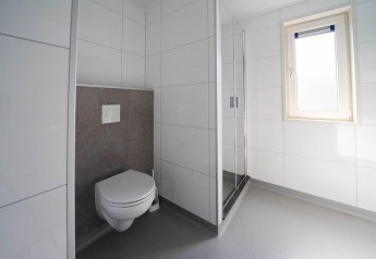 Baño moderno con inodoro suspendido, ducha y ventana en el Pavilion en EuroParcs Veluwemeer, Países Bajos.