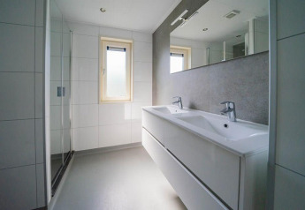 Bagno moderno con doppio lavabo, grande specchio e doccia al Pavilion di EuroParcs Veluwemeer, Paesi Bassi.