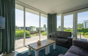 Woonkamer van Pavilion Waterfront lodge EuroParcs Veluwemeer, Nederland, uitkijkend over het water.