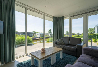 Woonkamer van Pavilion Waterfront lodge EuroParcs Veluwemeer, Nederland, uitkijkend over het water.
