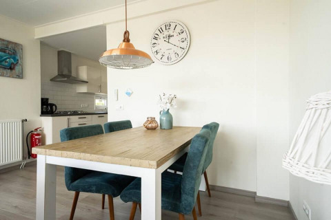 Eetkamer met houten tafel en blauwe stoelen in Pavilion Waterfront lodge bij EuroParcs Veluwemeer, Nederland.