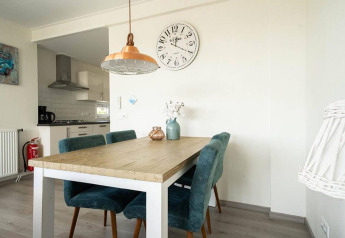 Eethoek met houten tafel en blauwe stoelen in Pavilion Waterfront lodge bij EuroParcs Veluwemeer, Nederland.