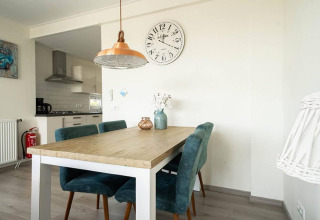 Dining area with wooden table and blue chairs in Pavilion Waterfront lodge at EuroParcs Veluwemeer, Netherlands.