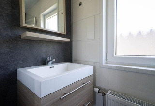 Moderno lavabo y espejo de baño en una cabaña de Pavilion Waterfront, EuroParcs Veluwemeer, Países Bajos.