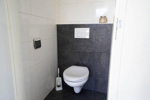 Toilettes modernes au Pavilion Waterfront d’EuroParcs Veluwemeer, Pays-Bas, avec WC suspendu et carrelage.