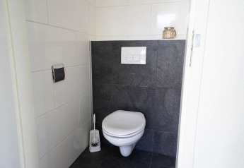 Bagno moderno al Pavilion Waterfront di EuroParcs Veluwemeer, Paesi Bassi, con WC sospeso e piastrelle.