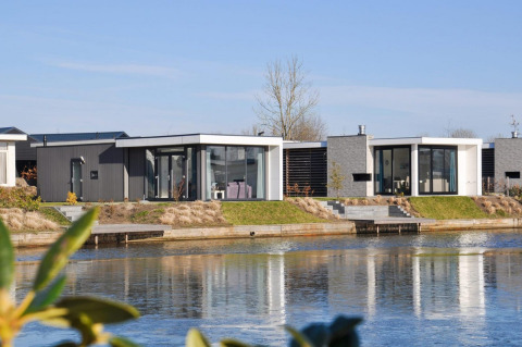 Moderne paviljoen-waterlodges bij EuroParcs Veluwemeer in Nederland, naast het water en omgeven door groen.