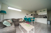 Sala de estar y cocina modernas en la lodge Pavilion Waterfront en EuroParcs Veluwemeer, Países Bajos.