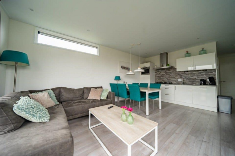 Sala de estar y cocina modernas en la lodge Pavilion Waterfront en EuroParcs Veluwemeer, Países Bajos.