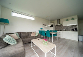 Sala de estar y cocina modernas en la lodge Pavilion Waterfront en EuroParcs Veluwemeer, Países Bajos.